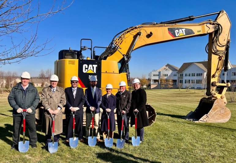 Figures posed in front of excavator