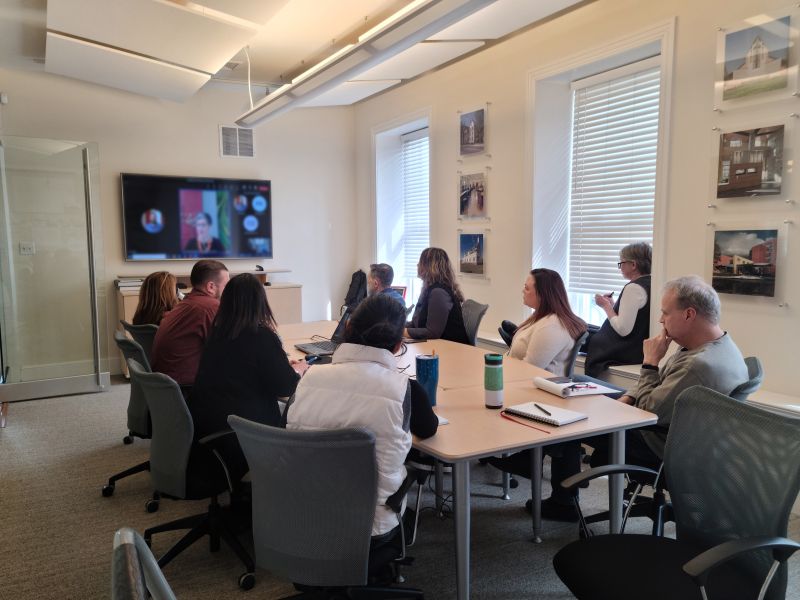 LRAI staff seated around a conference table, looking toward a wall screen